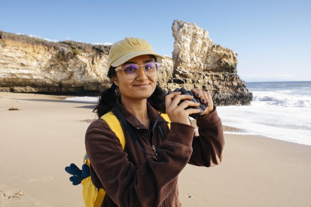 student on the beach with binoculars