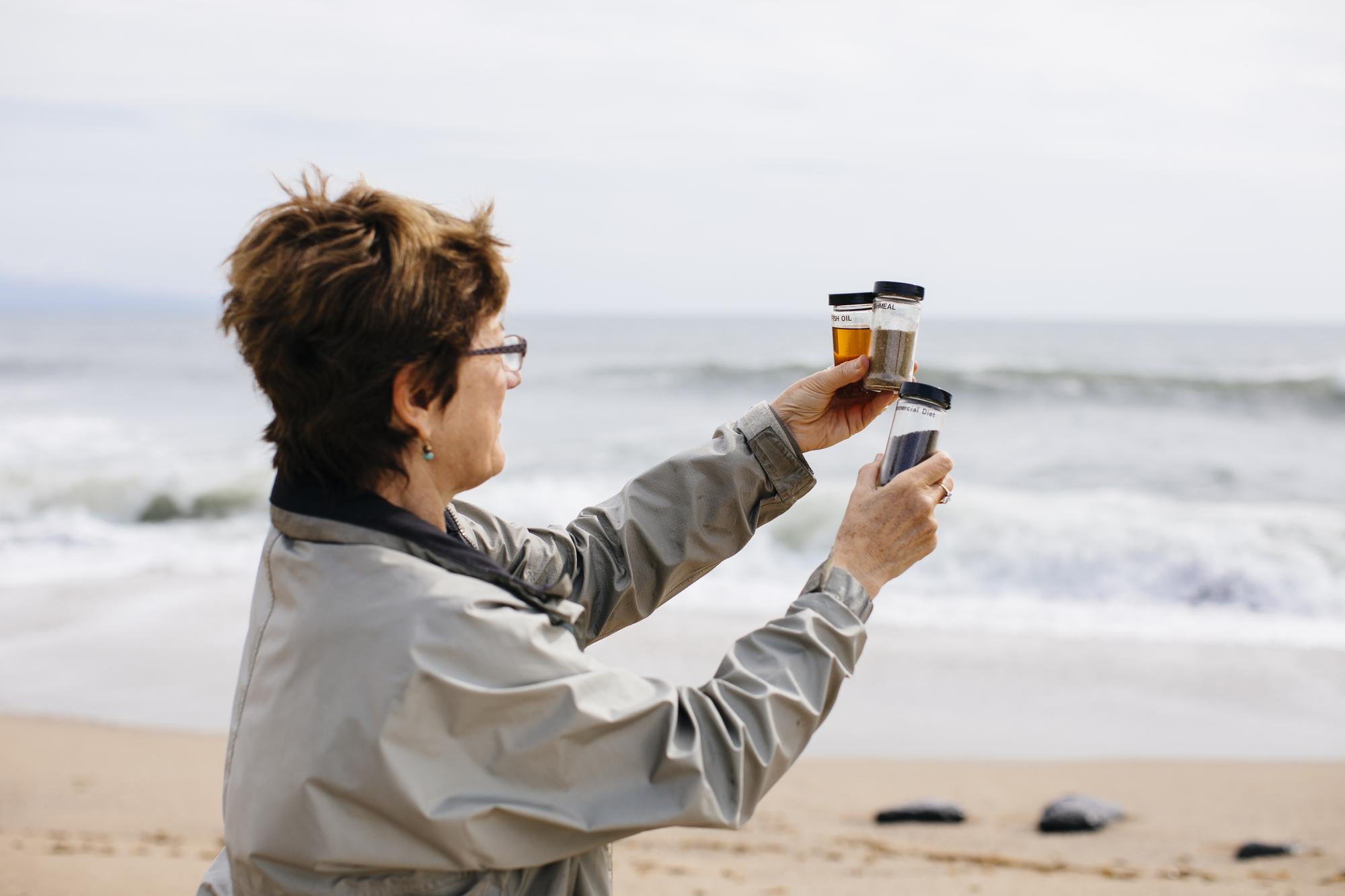 researcher on the beach  holding up water specimens.